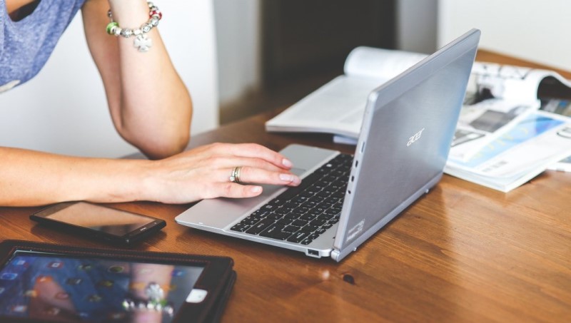 Image of the arms and hands of someone working at their laptop on a table.