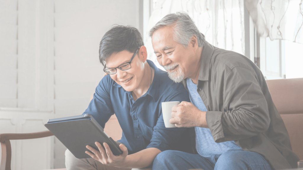 A father and son sit together, enjoying looking at something shown on a laptop computer