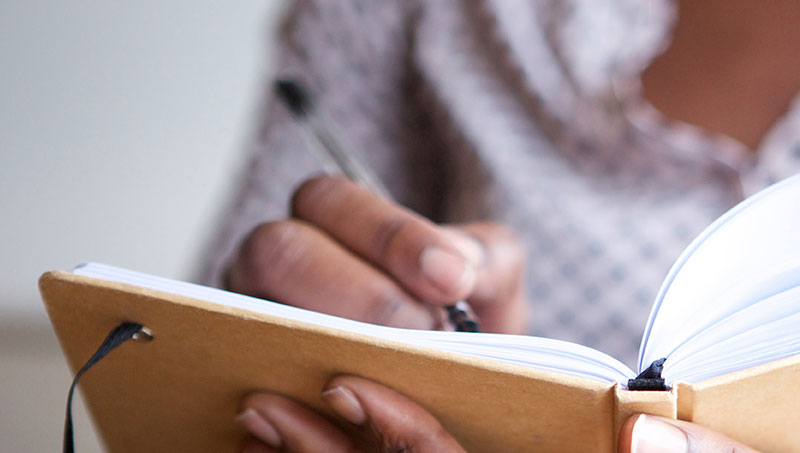 Someone writing in a notebook or diary.