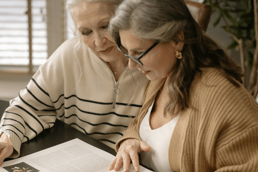 One lady interviewing another. Both are looking down at a manuscript.