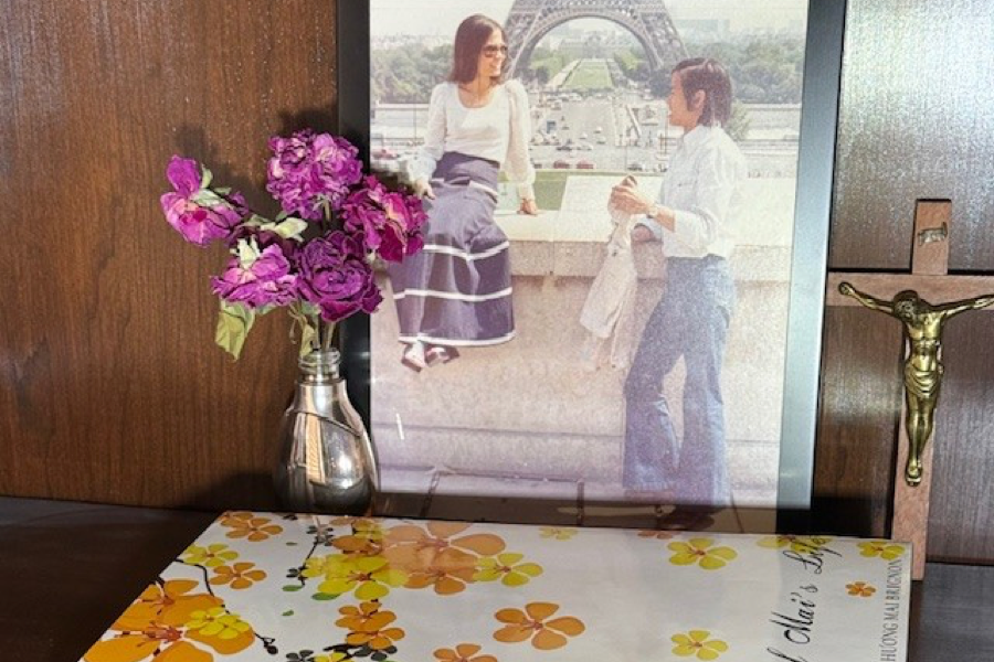 A photograph of private autobiography author Hu'o'ng Mai Brignon and her brother beside her LifeBook, Pieces of Mai's Life.
