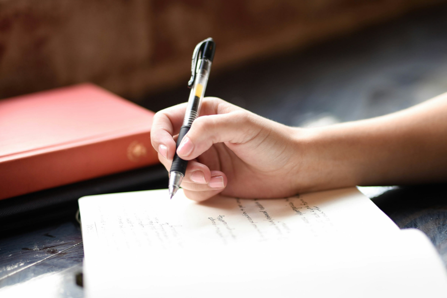 A hand holding a pen over a notebook.