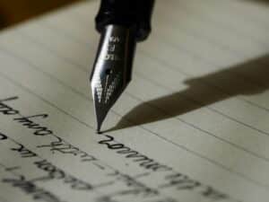 A fountain pen writing on a lined page.