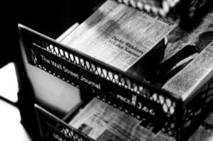 A black-and-white photograph of copies of The Wall Street Journal in a stand.