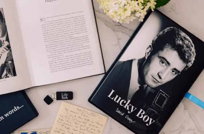 A memoir book, USB drive and presentation box on a table with a handwritten letter