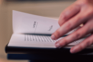 A close-up photograph of a hand turning the pages of a book.
