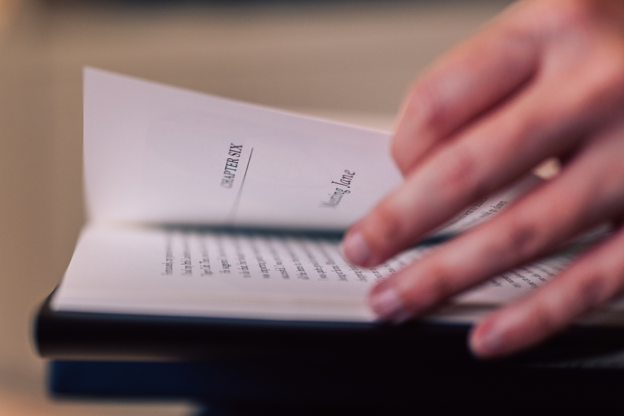 A close-up photograph of a hand turning the pages of a book.