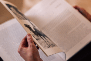 A close-up photograph of someone's hand leafing through the pages of a book.