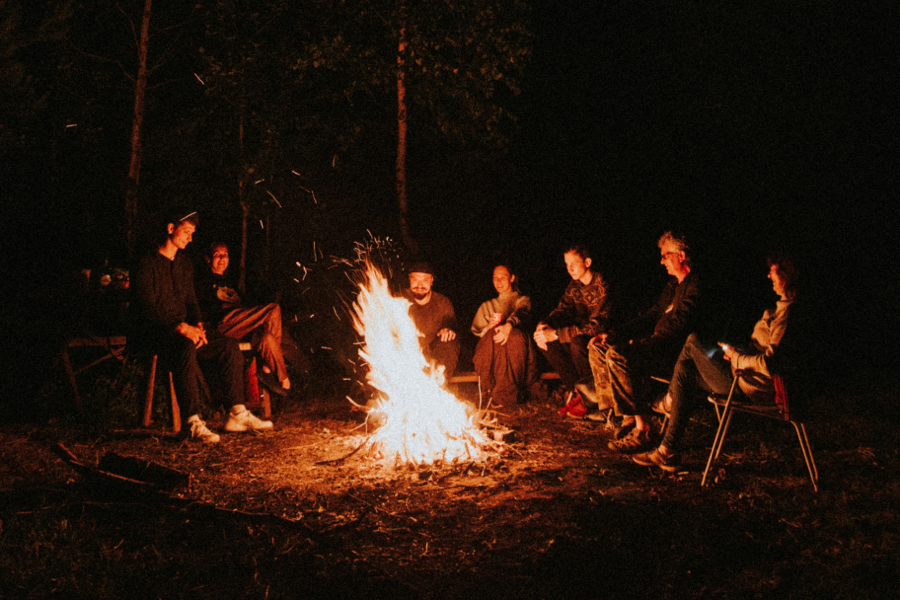 A photograph of people sitting around a fire in the dark, sharing stories and memories.