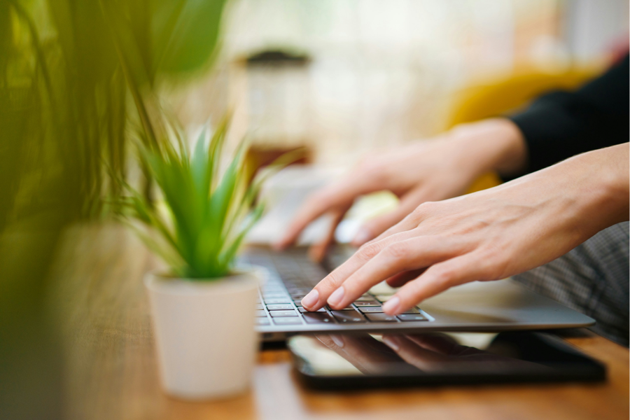 A close-up photograph of two hands typing on a laptop computer