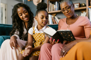 A photograph of three generations of women enjoying a book together.