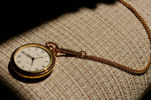 A photograph of a pocket watch resting on the arm of a chair